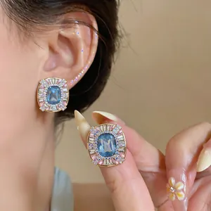 Detailed macro shot showing the intricate blue and pink crystal setting on gold stud earrings