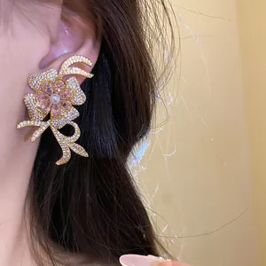 Close-up of elegant 18k gold-plated floral earrings with pink zirconia and pearl details