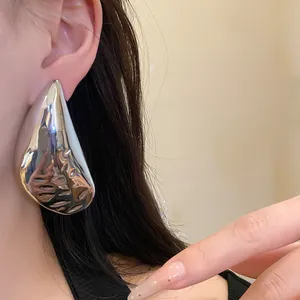 Close-up detail showing a large silver water drop earring worn on a model's ear