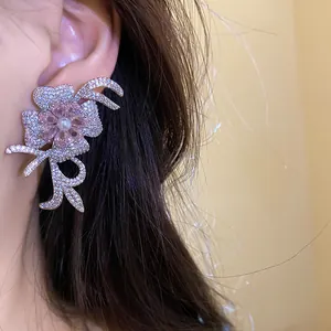 Close-up of 18k gold plated flower stud earring with sparkling zircon and pearl details