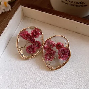 Elegant resin flower stud earrings with dried red gypsophila and gold irregular frame.