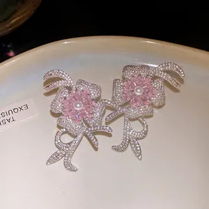 Close-up detail of 18k gold plated flower earrings with pink zircon and pearls.