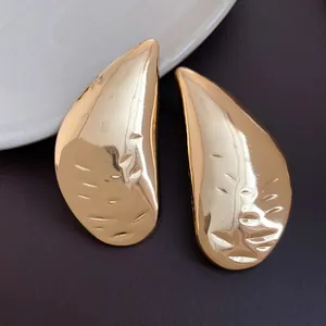 Macro view of polished gold teardrop earrings with a hammered metallic texture