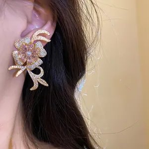 Elegant 18k gold plated flower stud earrings with pink zircons and pearl detail.