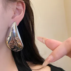 Close-up view of elegant minimalist silver waterdrop statement earrings worn by a model