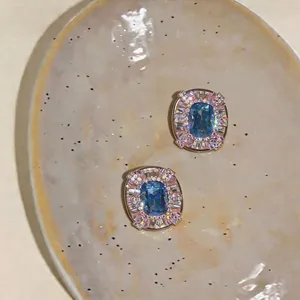 Close-up detail of blue and pink crystal geometric earrings on a ceramic dish