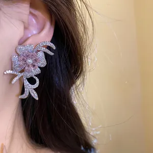 Close-up detail of a sparkling silver flower earring with pink crystal and pearl on ear
