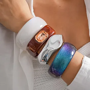 Close-up view of stacked chunky resin bracelets with square gemstone and glitter finish.