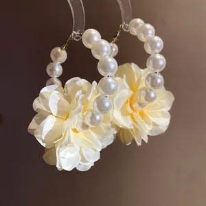 Vue macro détaillée d'élégantes créoles en perles avec de délicates fleurs en tissu jaune