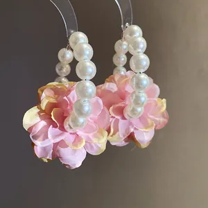 Gros plan détaillé de boucles d'oreilles créoles en perles rétro avec fleurs en tissu rose