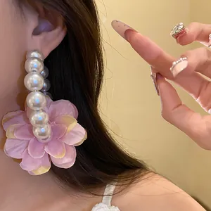Gros plan d'une boucle d'oreille en perles vintage avec une grande fleur en tissu rose