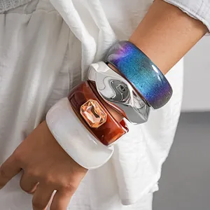 Detailed view of stacked resin bangles featuring rhinestones and metallic textures for women