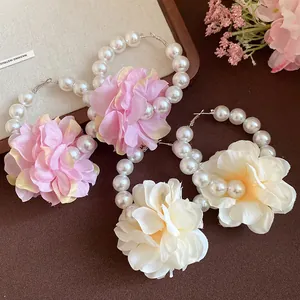 Vue détaillée de créoles en perles avec de délicates fleurs en tissu rose et blanc