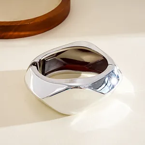 Close-up view of a minimalist silver geometric faceted bangle with a hinged opening