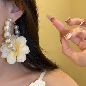 Gros plan de boucles d'oreilles créoles perles vintage avec détail fleur en tissu délicat.