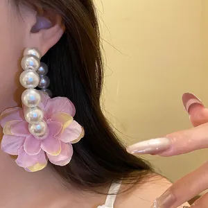 Gros plan détaillé de grandes créoles élégantes en perles avec une fleur en tissu rose