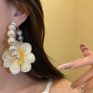 Détail d'une boucle d'oreille élégante en perles avec une grande fleur en tissu