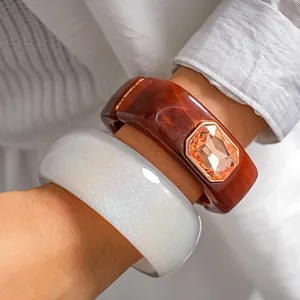 Detailed macro shot of chunky marbled resin bangles with faceted orange gemstone and glitter