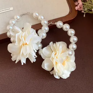 Vue détaillée de grandes créoles en perles avec d'élégantes fleurs en tissu blanc
