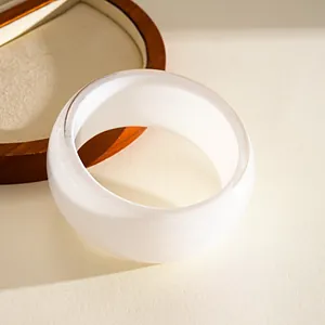Detailed close-up of a white resin bangle with shimmering finish on a wooden display