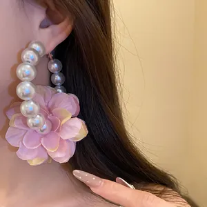 Gros plan sur une créole en perles vintage avec une grande fleur en tissu rose