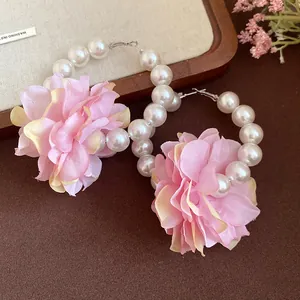 Détail de boucles d'oreilles perles avec fleurs en tissu rose et aiguilles en argent