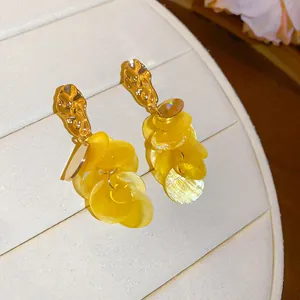 Detailed view of yellow shell tassel earrings with gold-toned metal accents for vacation.