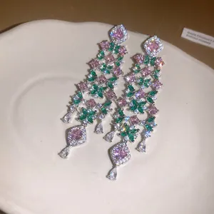 Close-up of long tassel flower earrings with pink and green stones in light luxury style