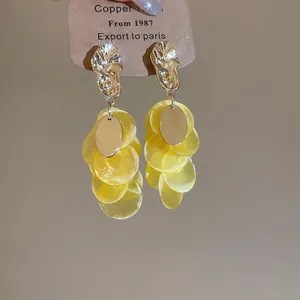 Close-up detail of yellow shell tassel earrings with elegant gold-tone studs for women