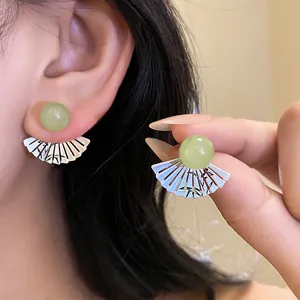 Close-up of retro ethnic fan-shaped stud earrings featuring a vibrant green resin bead