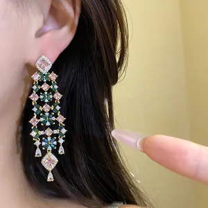 Detail view of 18k gold plated long tassel earrings with green and pink zircons.