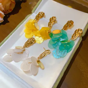 Detailed view of gold-tone shell tassel earrings in white, yellow, and teal shades.