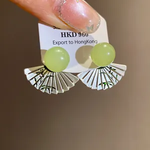 Detail view of retro fan-shaped earrings with green resin beads and bamboo pattern.