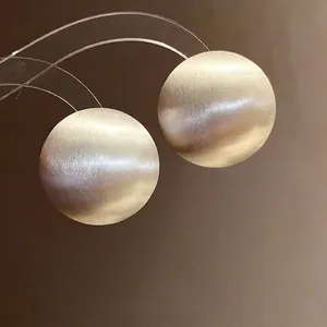 Elegant minimalist round brushed metallic stud earrings featuring high-end refined texture.