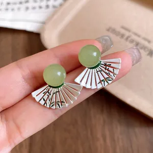 Detailed close-up of retro fan-shaped earrings with green beads and bamboo patterns
