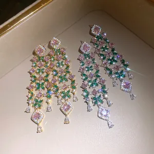 Detailed macro view of elegant 18k gold plated earrings with pink and green zircon floral tassels
