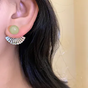 Close-up detail of vintage resin round stud with silver fan pendant earring on ear