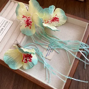 Close-up of elegant fabric flower hair clips with long beaded tassels in a jewelry box