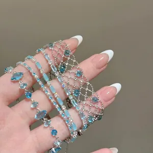Macro detail of stacked blue gemstone lace bracelets with intricate silver-tone chains