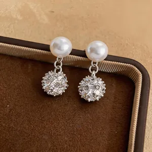 Primo piano dettagliato di orecchini di perle francesi con pendenti a sfera pavé luccicanti