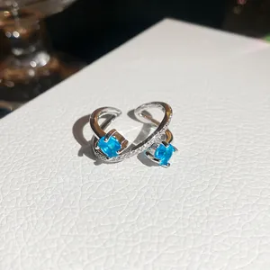 Close-up of elegant silver open ring with dual blue zircons and pavé diamonds