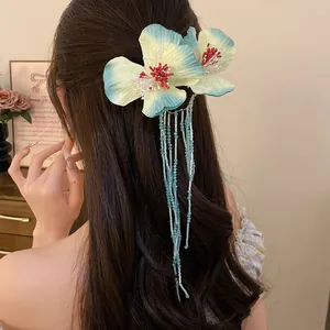 Detailed view of bohemian fabric flower hair clip with long beaded tassels on dark hair