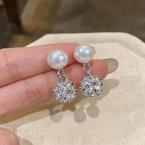 Macro dei lussuosi orecchini a perno con perle e pendenti a sfera con strass