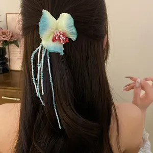 Elegant bohemian fabric flower hair clip with blue beaded tassels on long dark hair