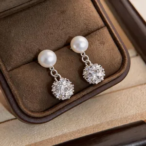 Primo piano di eleganti orecchini di perle in stile francese con pendenti a sfera di diamanti