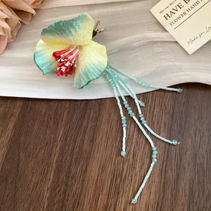 Close-up detail of forest style fabric flower hair clip with long light blue beaded tassels