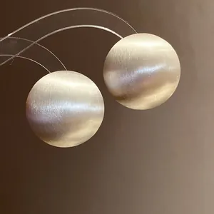Macro detail of silver sphere stud earrings featuring a refined brushed metallic finish texture