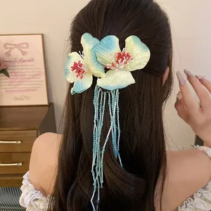 Close-up of fabric flower hair clip with light blue beaded tassels on long hair