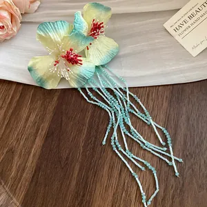Detail shot of a forest-style floral hair clip featuring teal tassels on a wooden surface