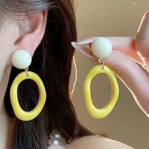Vibrant yellow and white acrylic geometric drop earrings in trendy summer dopamine style.